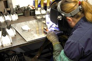 Female worker with welding mask on welding parts